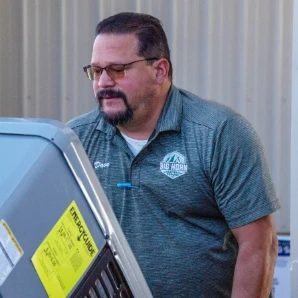 HVAC service professional examining a residential air conditioning system.