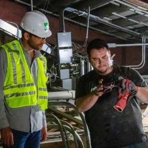 HVAC technicians inspecting and repairing equipment in a commercial mechanical room.